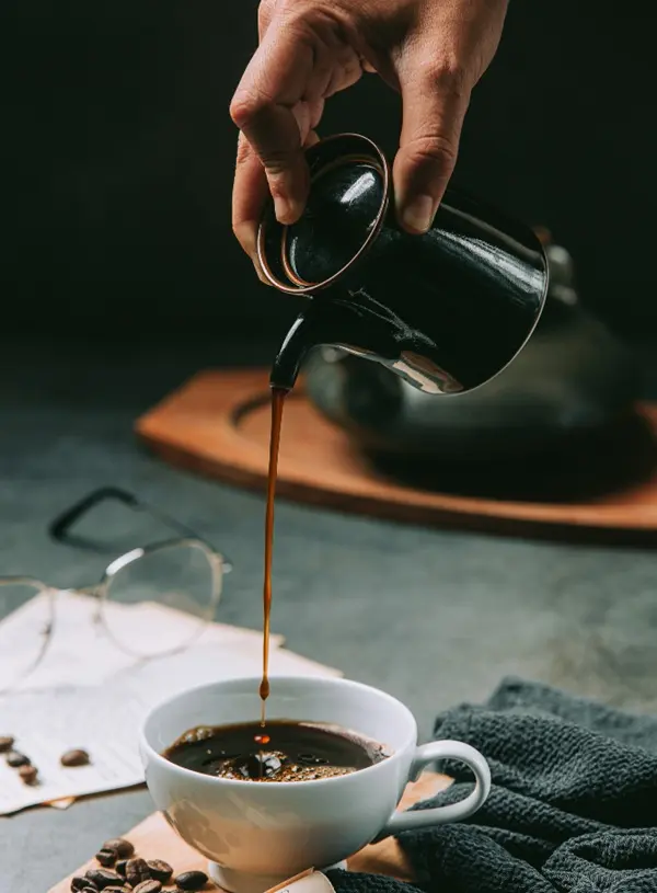 Bàn tay đang rót cà phê rơi xuống